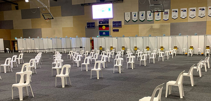 Photograph of a large hall with many chairs placed socially-distant.