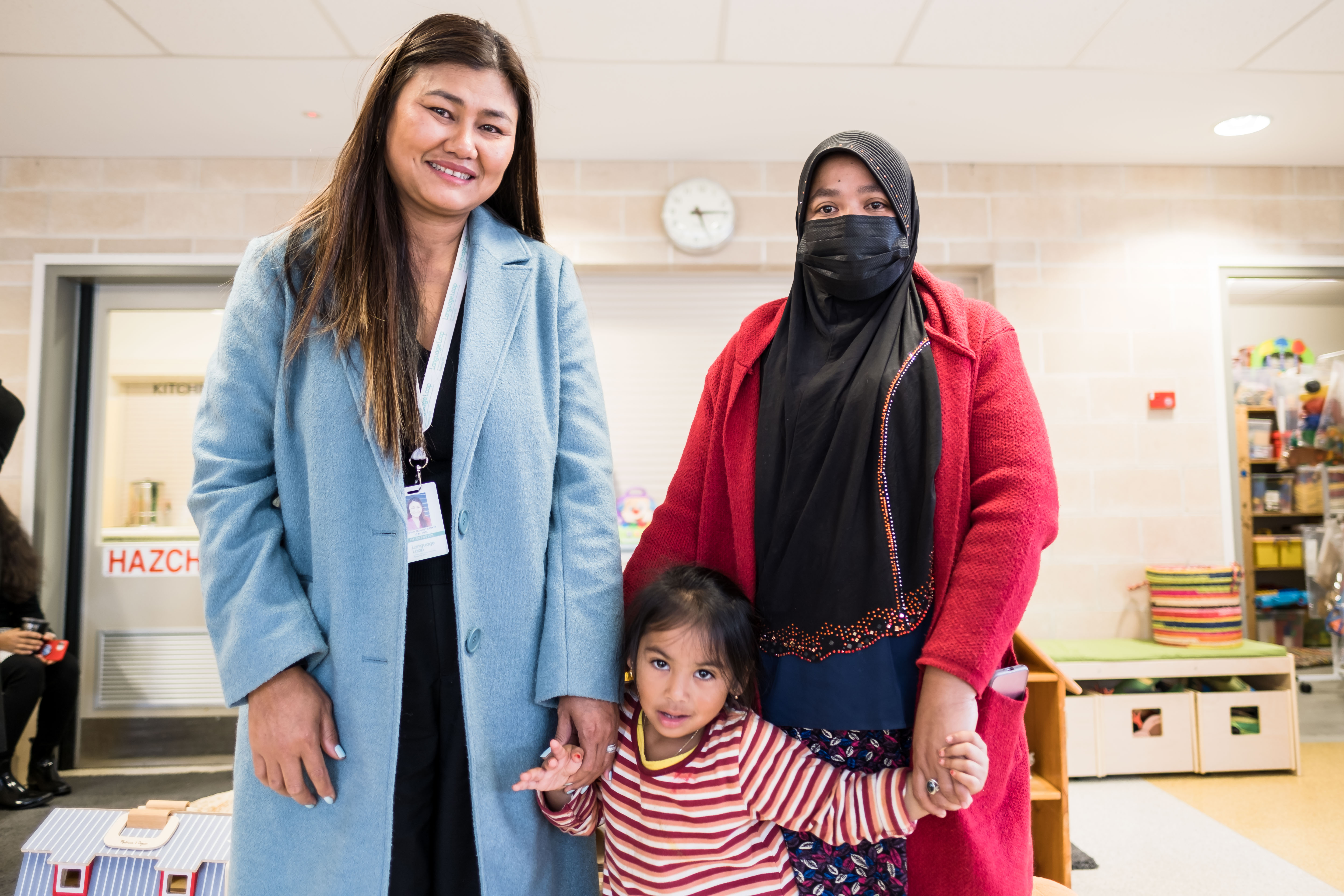 Mum and Daughter standing next to a CALD worker in a Kindergarten 