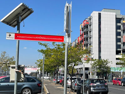 Outdoor scene of park, with RACISM NOT WELCOME sign